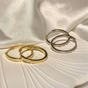 Orecchini a cerchio minimalisti oro e argento su piatto a conchiglia con seta bianca
