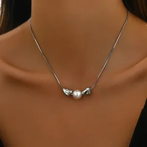 Detailansicht der silbernen Schlangenkette mit weißer Perle und glänzenden Metallperlen