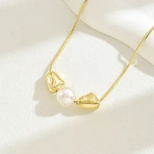 Detailansicht der langen goldenen Schlangenkette mit weißer Perle und Goldperlen