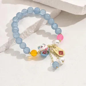Detailaufnahme der Winkekatze-Perlenarmband mit blauen Edelsteinen auf weißem Stein