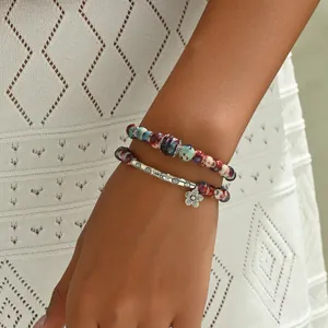 Detail of bohemian beaded bracelets with floral pendant and ethnic porcelain beads