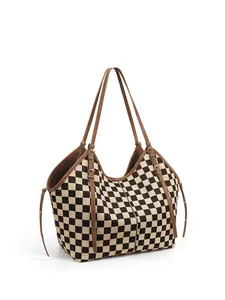 Side view of checkerboard tote bag with brown leather handles and buckle details
