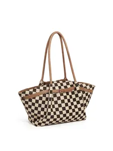 Close-up of checkerboard tote bag showing brown leather handles and metal buckle detail