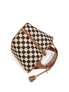 Détail du sac seau en toile damier montrant les anses en cuir brun et les fermoirs dorés