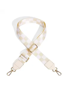 Detail of checkered canvas bag strap with golden metal hooks and adjustable buckle