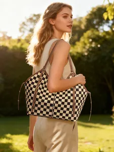 Macro shot of large checkerboard tote bag with premium brown leather straps and metal buckle