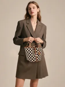 Sac seau à damier avec garniture en cuir marron porté par un mannequin