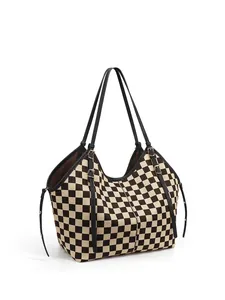 Detail of checkered tote bag with leather straps and gold metal hardware accents