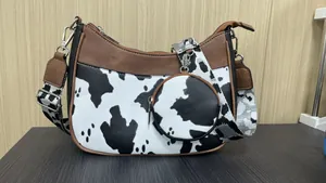 Detail of cow print crossbody bag with wide patterned strap and matching round coin purse