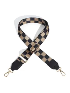 Close-up of checkerboard wide bag strap with gold metal hooks and black leather ends