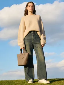 Detailopname van een taupe PU-emmer-tas gedragen door een model in een buitenomgeving