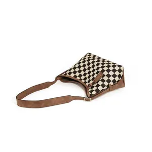 Detailed view of checkered tote bag featuring brown suede texture and adjustable strap
