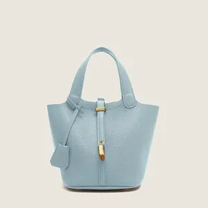 Close-up of sky blue lychee grain leather bucket bag with golden padlock and metal hardware
