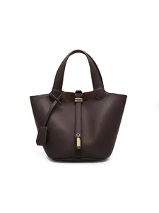 Detail view of pebbled PU leather texture and gold metal lock on dark brown bucket bag