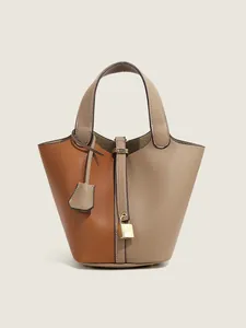 Detail of two-tone pebbled leather bucket bag featuring gold padlock and key charms