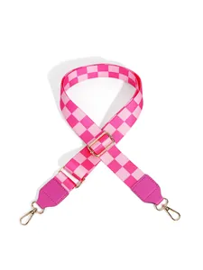 Close-up of pink checkered wide bag strap with golden lobster clasps and leather ends