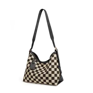 Close-up of checkerboard hobo bag with black leather strap and gold metal buckle