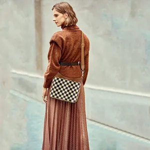 Retro-Schultertasche mit Schachbrettmuster und braunen Riemen am Model im Freien
