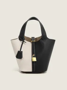 Close-up of contrast leather bucket bag featuring lychee grain texture and gold padlock