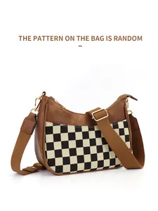 Detail of checkered pattern fabric and adjustable brown shoulder strap on crescent bag
