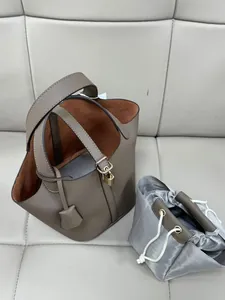 Detail view of dark brown pebbled leather bucket bag with lock and herringbone liner