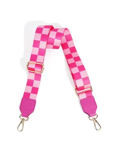 Close-up of pink checkered woven bag strap with golden metal lobster clasps