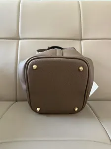 Detail of brown leather bucket bag with litchi grain and four golden protective metal feet