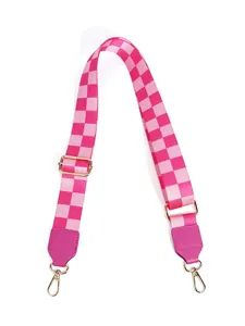 Detail of pink checkerboard nylon bag strap with adjustable gold-tone buckle