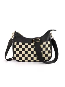 Detail of adjustable woven strap and gold hardware on checkerboard crescent bag