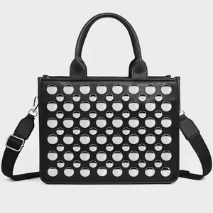 Detailed close-up of a black PU leather tote bag with silver metal rivets and wide strap