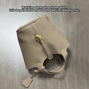 Detailed view of grey PU leather bucket bag with litchi texture and gold padlock charm