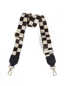 Detail of adjustable black and white checkered bag strap with gold metal hooks