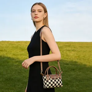 Mini sac à bandoulière en damier avec poignée marron sur fond de pelouse verte