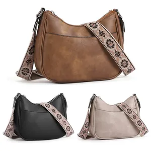 Close-up of crescent shoulder bags in three colors featuring vintage embroidered straps