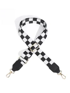 Detail of adjustable checkered bag strap with black leather ends and gold metal buckles
