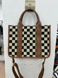 Checkered tote bag detail with brown faux leather trim and adjustable shoulder strap