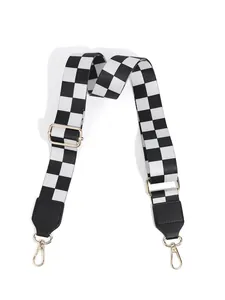 Macro shot of adjustable checkered bag strap with golden rotating hooks and black leather ends