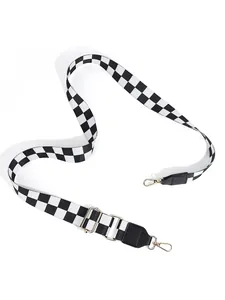 Detail of adjustable black and white checkerboard purse strap with gold metal lobster clasps