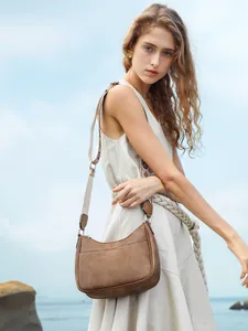 Detail of vintage brown crescent bag with patterned woven strap on female model