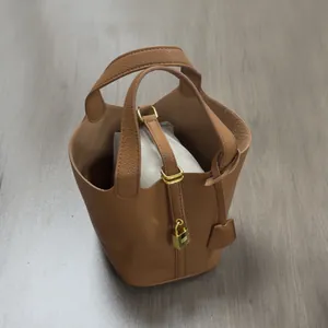 Top view of brown lychee grain PU bucket bag with gold lock and herringbone fabric liner