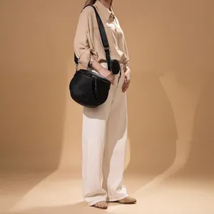 Schwarze Halbmond-Schultertasche aus Narbenleder mit Quasten und kleinem Münzfach am Model