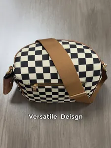 Detail view of checkerboard shell bag featuring adjustable wide strap and gold zipper