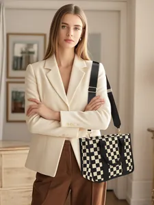 Woman in beige blazer wearing black and white checkerboard tote bag with wide strap