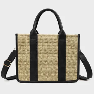 Detailed macro view of woven straw tote bag with black leather straps and gold metal buckles