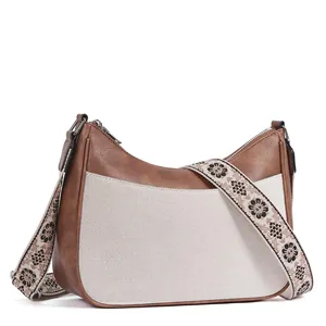 Detail of bohemian crescent bag featuring floral embroidered strap and faux leather texture