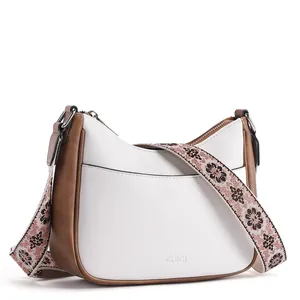Detail of white crescent bag with brown trim and floral jacquard adjustable strap