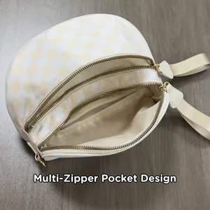 Detail of checkered crossbody bag showing multi-zipper pocket design and interior storage
