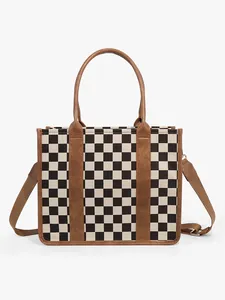 Detail view of large checkered tote bag with brown leather straps and sturdy canvas stitching