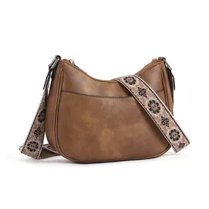 Brown vintage leather crescent crossbody bag with floral woven adjustable strap
