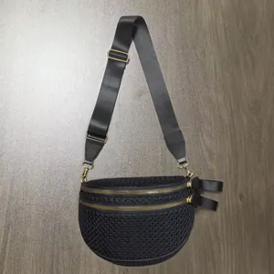 Close-up of black mesh crossbody bag featuring dual golden zippers and adjustable strap